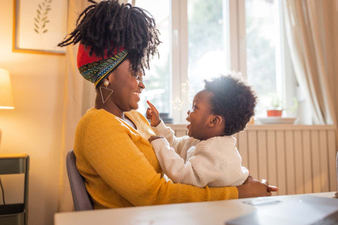 Single mother with son at home. She is using computer for paying bills or online shopping.